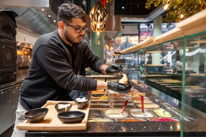 Een medewerker vult een gözleme bij de open keuken van Ekmekci